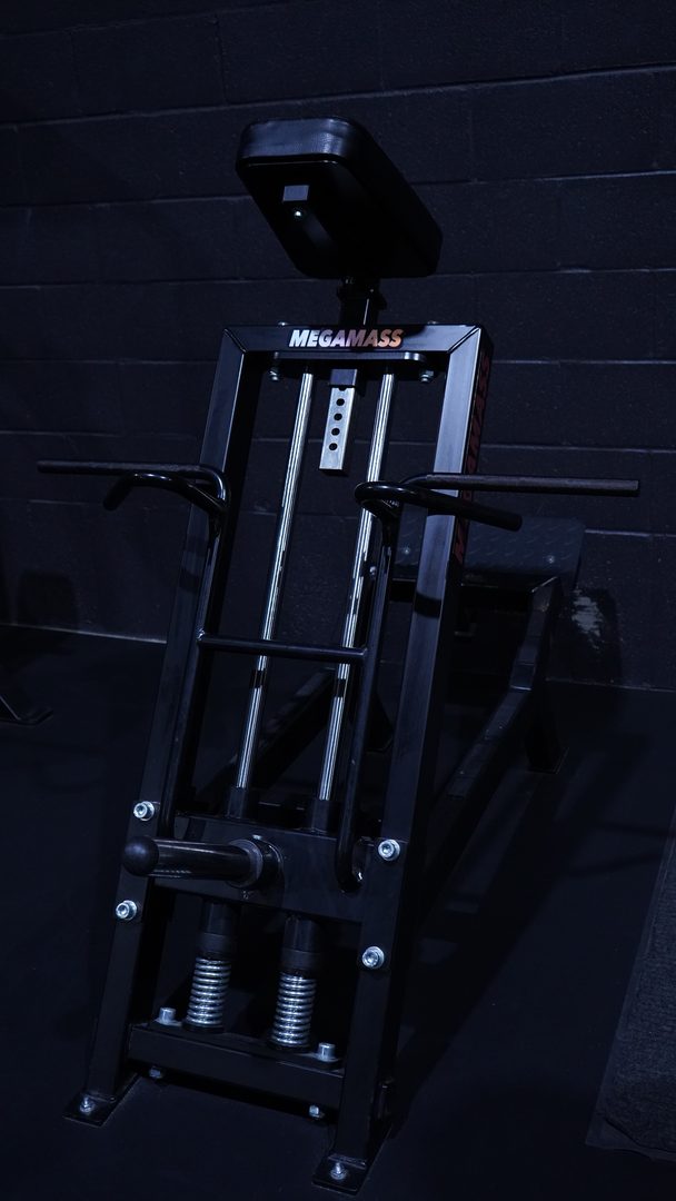 Black plate loaded machine against a dark block wall in blue light
