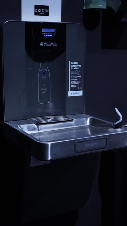 Bottle refilling station with Origin Gym sign above